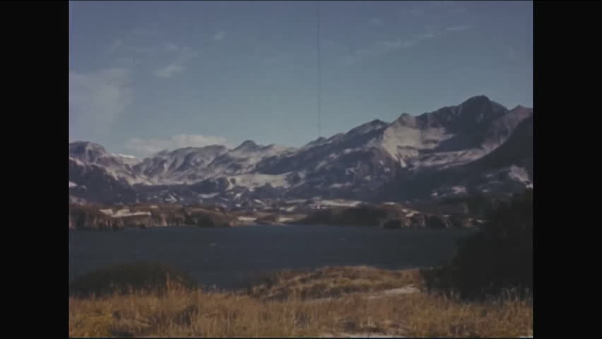 CIRCA - 1952 - Panorama of a snow-capped mountain range in Alaska near a lake.