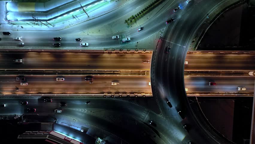 Financial technology, energy power, beautiful top view time-lapse of car traffic at roundabout lane and buildings. 4K drone aerial zoom out. Urban cityscape concept or abstract of advanced innovation.