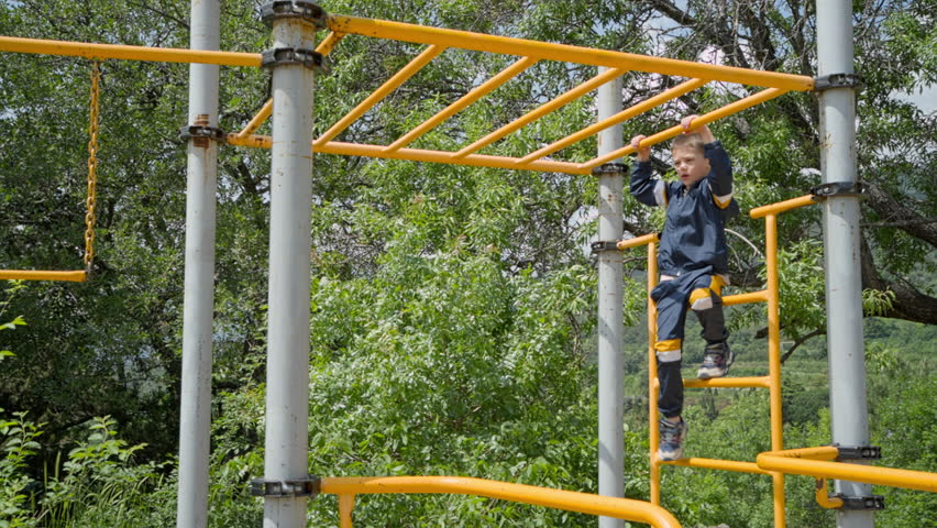 A 7-year-old boy is climbing the metal rungs of a sports field. Sports have been a great foundation for the development of the human body since a young age. 