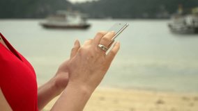 Female hands. The woman holds phone in hand against the background of a bay with boats. Beautiful woman using smart phone on beach. Vietnam.
