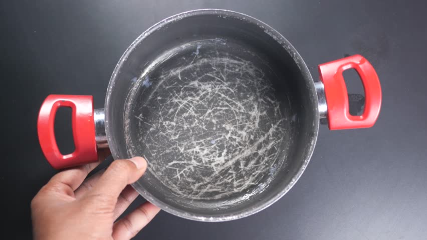 Hand holding scratched frying pan.