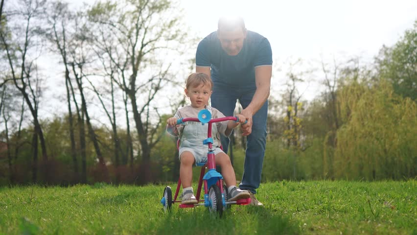 happy family. father teaches his baby toddler son to ride a bike. happy family kid dream concept. kid toddler learns to ride a bike with his father in park lifestyle, parent helps son playing - Powered by Shutterstock - Get 15% off with code: PIKWIZARD15