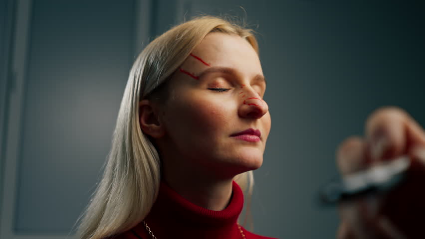 in a plastic surgery clinic a doctor makes markings on the face of a young girl before surgery