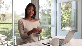 Mixed ethnicity (Asian-African) woman works on her laptop while working from home. Money falling around her in slow motion. - Powered by Shutterstock - Get 15% off with code: PIKWIZARD15