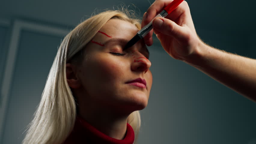 low shot in a plastic surgery clinic a doctor makes markings on the face of a young girl before surgery