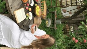 young woman model plus size in white dress sit at table with pet dog poodle, resting and drinking tea after harvesting autumn in back yard, fall and harvest, eco-friendly simple life, vertical video - Powered by Shutterstock - Get 15% off with code: PIKWIZARD15