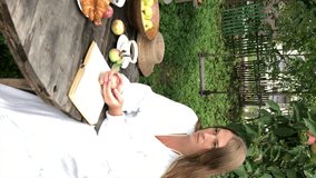 young woman model plus size in white dress sit at table with pet dog poodle, resting and drinking tea after harvesting autumn in back yard, fall and harvest, eco-friendly simple life, vertical video - Powered by Shutterstock - Get 15% off with code: PIKWIZARD15