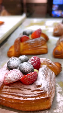 Freshly baked pastries adorned with vibrant berries on rustic table setting. Gourmet breakfast and indulgence.