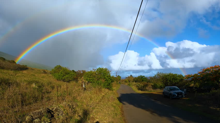 Bright double rainbow above the country road and prairie. Colourful double rainbow in the steppes of Maui island, Hawaii.