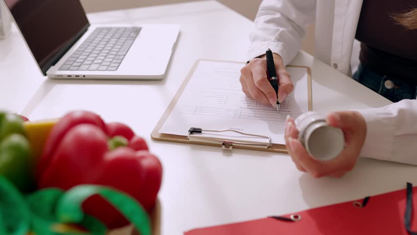 Closeup view of female nutritionist hands preparing diet plan for patient at consultation. Nutrition and diet concept.