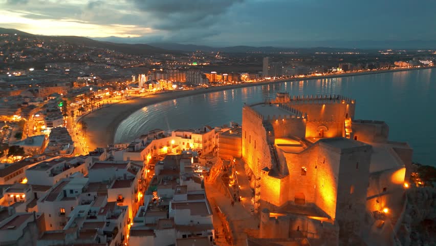 Aerial view of Peniscola beach and castle at twilight, Peniscola is a popular coastal town on Costa del Azahar, Province of Valencia, Spain. Drone night shot of medieval Spanish town