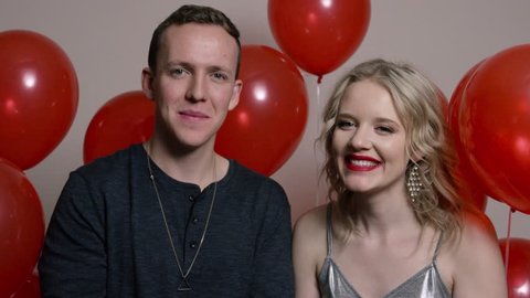 Happy Couple Surrounded by Red Balloons Throw Glitter in the Air