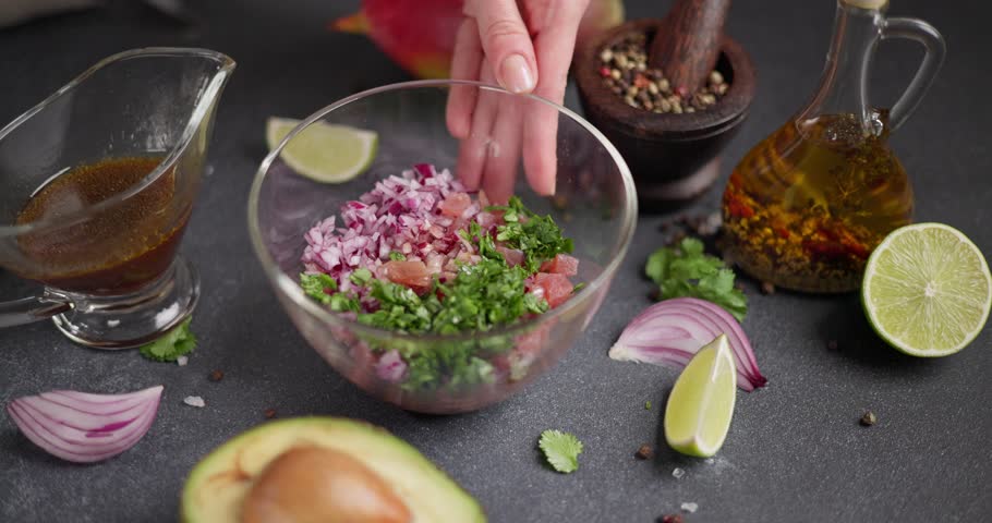 Woman mixing chopped tuna, cilantro and onion in a glass bowl cooking traditional tuna tartare