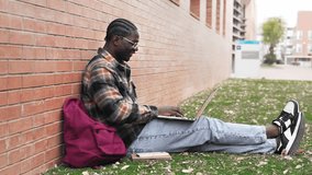 African American student using laptop computer learning online sitting in university campus grass  - Powered by Shutterstock - Get 15% off with code: PIKWIZARD15