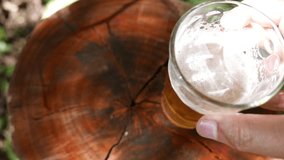 POV of a person placing a glass of beer on the table. A top view of a fresh drink. A cold beer glass on a wooden table in the garden. Close-up of a beer foam. A beer jar under random rays of sunlight - Powered by Shutterstock - Get 15% off with code: PIKWIZARD15