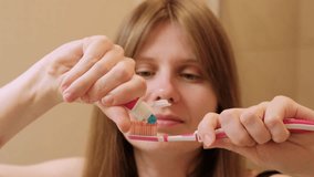 Woman puts toothpaste on her toothbrush. Girl squeezing blue toothpaste from a tube onto toothbrush. Close up female face and hands - Powered by Shutterstock - Get 15% off with code: PIKWIZARD15