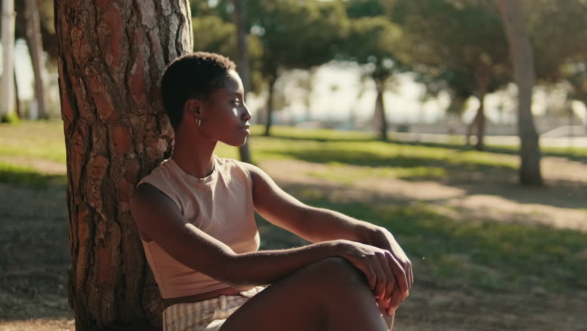 Portrait of young woman in casual clothes chilling outdoors among the trees in the park, union with nature and mental health concept