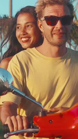 Young happy couple of Caucasian man driving scooter and Hispanic woman raising hand up enjoying summer vacation with boyfriend and traveling to tropical island. Multiethnic love concept