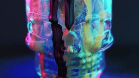Ink skull. Glitter fluid drip. Occult spell. Defocused neon light black blue pink golden color shiny texture paint flow skeleton head on dark abstract art background. - Powered by Shutterstock - Get 15% off with code: PIKWIZARD15
