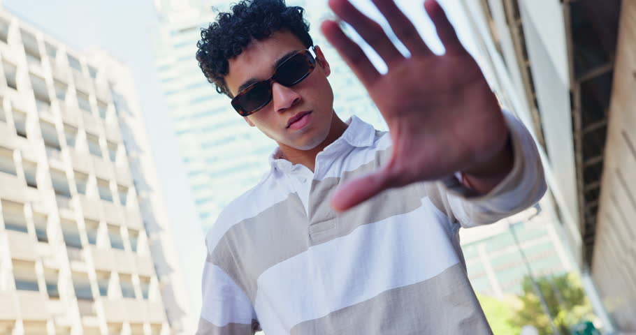 Man, fashion and frame of hand in city for urban style, confidence and designer outfit. Male person, serious and sunglasses with gesture by buildings for trendy, clothes and streetwear in low angle