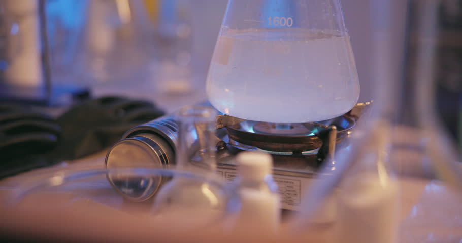 Science, flask and liquid on gas for danger in lab as experiment with nitrogen, chemicals and spray for flames as research. Study, chemistry and glass container with fuel or water for biology test