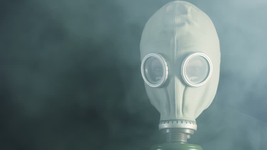 Black background. Thick smoke hides man in a gas mask. The smoke dissipated