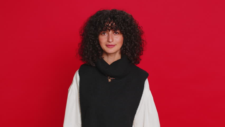 Ready to eat. Hungry Caucasian woman with curly hair waiting for serving dinner dishes with with restlessness holding cutlery fork knife, will appreciate delicious restaurant meal on red background