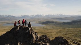 Big group of diverse tourists or hikers are standing on mountain top with great view at valley with sunset lakes and snowy mountains. Drone flights around peoples on big rock - Powered by Shutterstock - Get 15% off with code: PIKWIZARD15