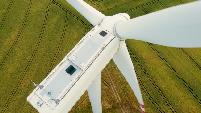 Close up wind turbine spinning over farmers fields at sunset. Electricity, ecological saving and alternative power source