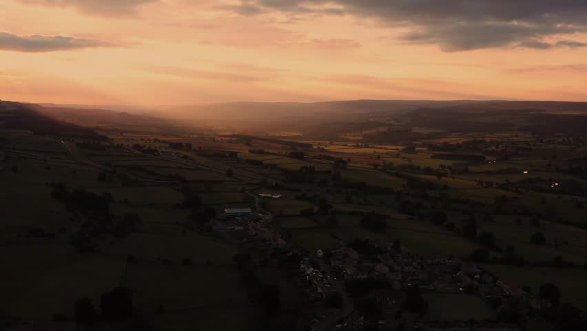 Aerial footage at sunset in the beautiful village of Middleham, Leyburn in North Yorkshire in the UK showing the sun setting behind the British village in the summer time at dusk