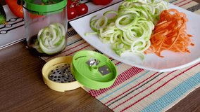 Sliced vegetables and container of vegetable slicer on kitchen table. 