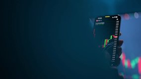 Tracking shot of female stock trader checking stock market data using mobile phone, scrolling, touching stock market chart on touch screen device, blurred computer monitor with chart of background. - Powered by Shutterstock - Get 15% off with code: PIKWIZARD15