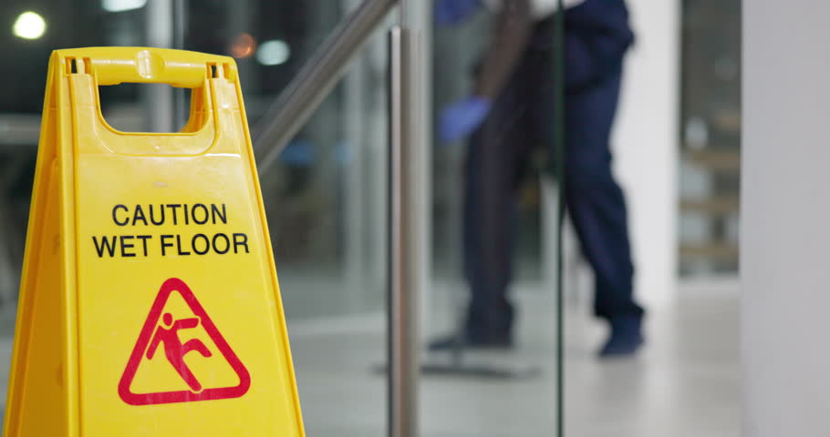 Person, mopping and office with caution sign, janitor and hygiene service and wet floor for healthcare. Attention, safety and warning for risk, dancing and cleaner happy for cleaning or maintenance