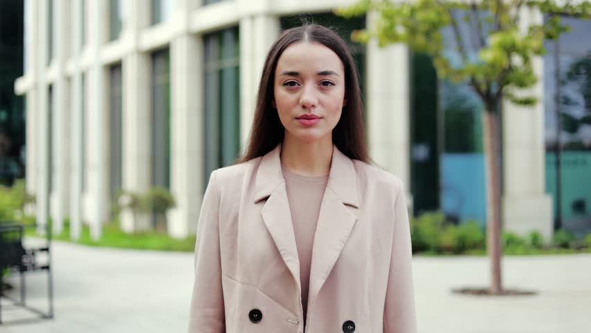 Serious female closing mouth with imaginary zip and pretending throwing key away while looking at camera. Reliable person in elegant clothes promising keeping secrets and not telling anyone info.