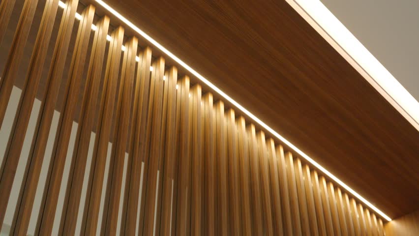 Modern interior wall design featuring vertical wooden slats with integrated lighting. Warm glow highlighting natural pattern and creating elegant atmosphere indoors
