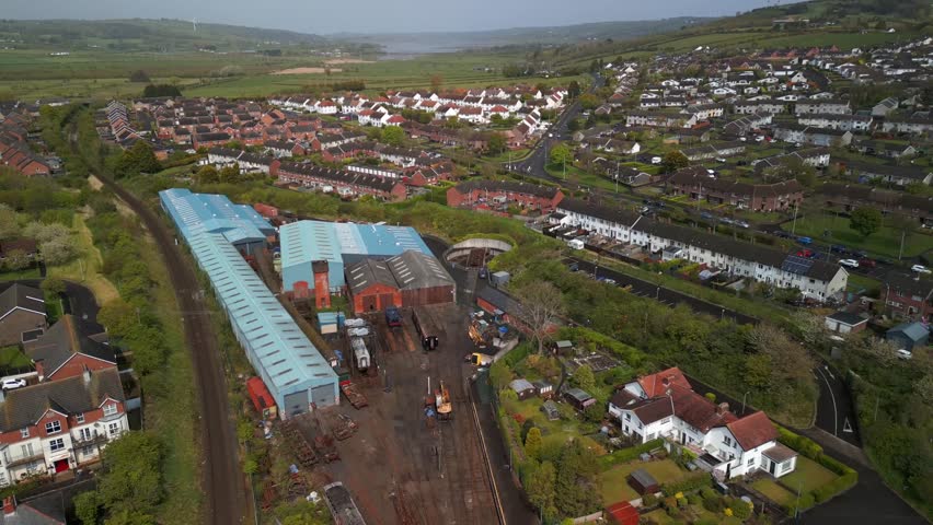 Aerial of a vintage railway station in Whitehead, Northern Ireland. The camera lowers from above to show tracks, signal box and trains. Produced in 4K, 60 frames per second and Rec709 color space.