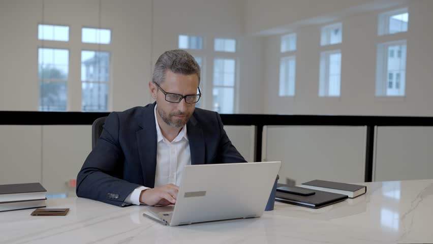 Office worker with laptop at office. Ofice employee remote working in modern office. Businessman have on line meeting. Business man using computer in office. Modern offices workplace.
