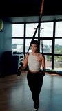 Beautiful woman doing exercise with trx system.Fitness exercises with loops.Concept workout healthy lifestyle sport.Vertical video