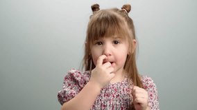 Background video of children's emotions, a portrait of a girl sticking her finger in her nose. Interesting childhood games and smiles. High quality 4k footage