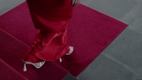 An elegant woman in a flowing red dress walks on a luxurious red carpet, wearing white high heels. The image exudes glamour and sophistication, perfect for events and fashion themes. - Powered by Shutterstock - Get 15% off with code: PIKWIZARD15