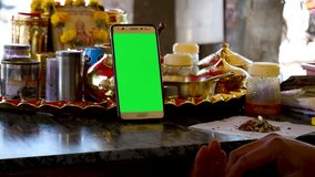 indian shopkeeper working and surfing internet on mobile ( green screen display ) useful for mobile advertisment application - digital marketing 