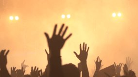 This image captures a lively concert scene with hands raised high in the air, illuminated by bright yellow stage lights. The silhouettes of the crowd create an energetic and vibrant atmosphere - Powered by Shutterstock - Get 15% off with code: PIKWIZARD15