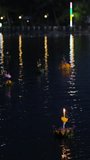 Vertical video. Krathongs floating on Lake Khao Tao reservoir at Loi Krathong festival in Thailand