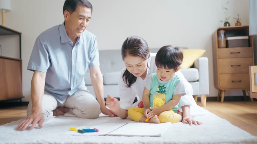 A senior couple drawing with their 2-year-old grandson