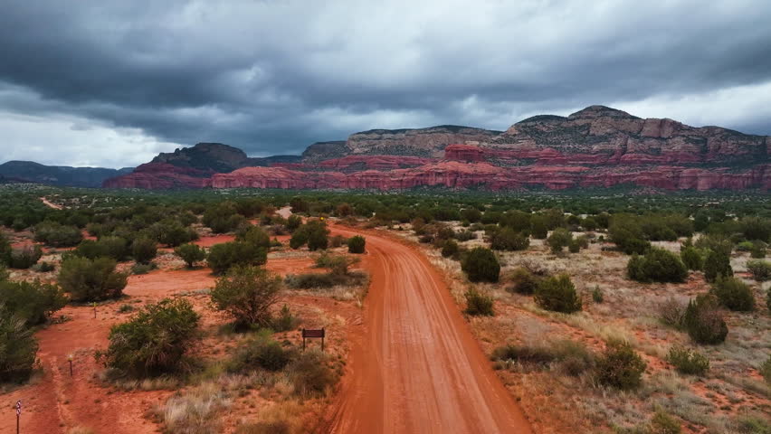 Lonely Dirt Road Towards Grand Canyon National Park With Cloudy Sky In Sedona, Arizona. Aerial Shot