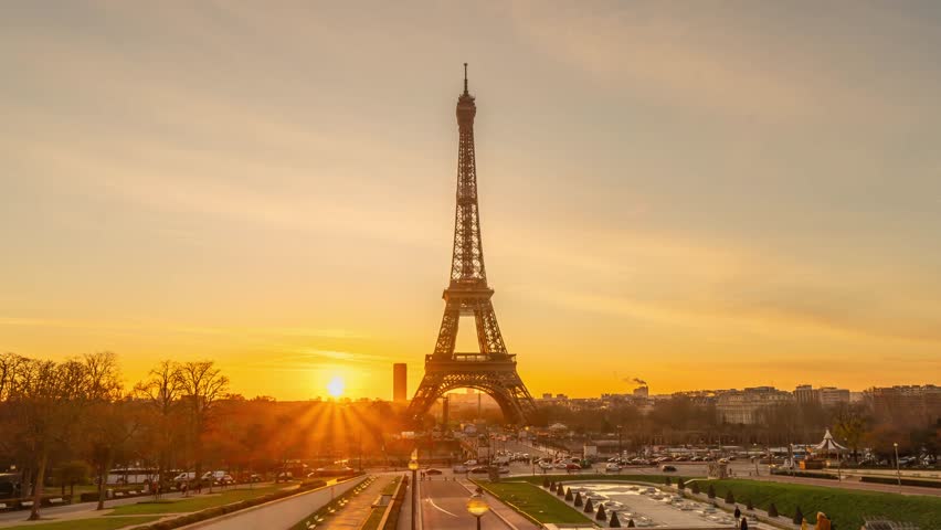 4K timelapse of Paris at sunrise with the Eiffel Tower at the Trocadero gardens and the traffic,the most famous landmark in Paris,France.Golden hour in a cloudy sunny morning