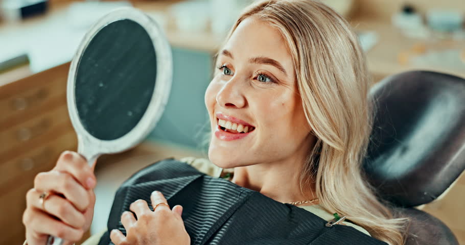 Woman, happy and healthcare with mirror for results, oral hygiene and teeth whitening at dentist in chair. Patient, smile and dental care at orthodontist for tooth cleaning, veneers and implants