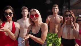Teenagers models have rest on holidays near swimming pool in swimwear. Couples flirting and sending air kisses on summer club party, dancing, waving and laughing with friends in bikinis. - Powered by Shutterstock - Get 15% off with code: PIKWIZARD15