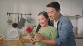 Asian mature man surprise and give rose flower to his beautiful wife. Attractive romantic couple male and woman spending time to celebrate anniversary and valentine's day together in kitchen at home. - Powered by Shutterstock - Get 15% off with code: PIKWIZARD15