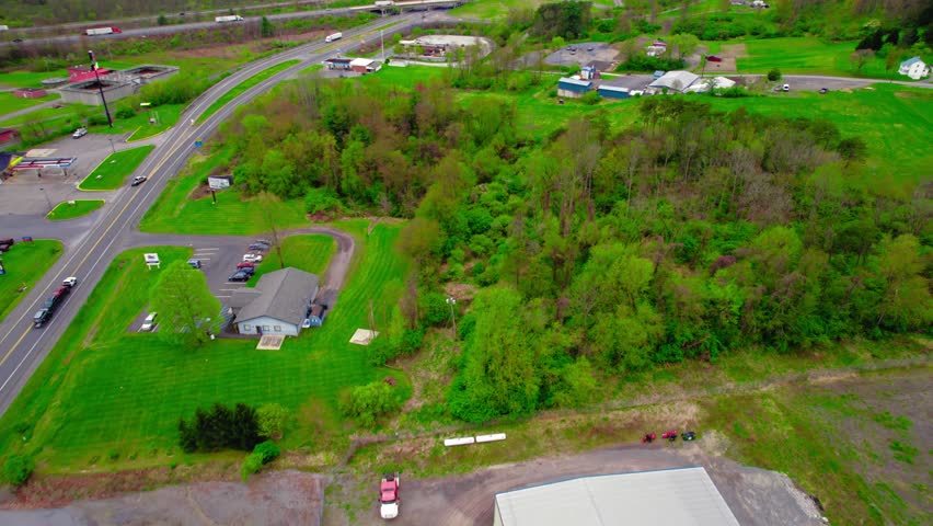 Springtime aerial view of a pickup truck pulling a wedge trailer with cars on a rural highway, illustrating the car hauling industry. PA, USA